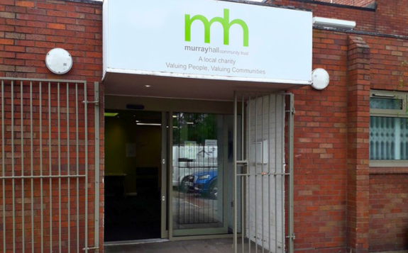 Brick building entrance to MD Support Centre Coventry with yellow-framed glass doors, signage displaying unit numbers 9 and 10, and a banner beside the doorway.