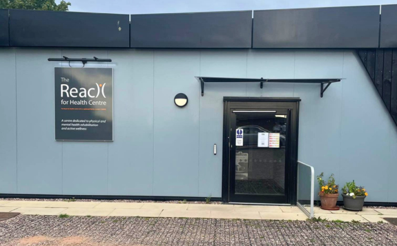 Brick building entrance to MD Support Centre Coventry with yellow-framed glass doors, signage displaying unit numbers 9 and 10, and a banner beside the doorway.